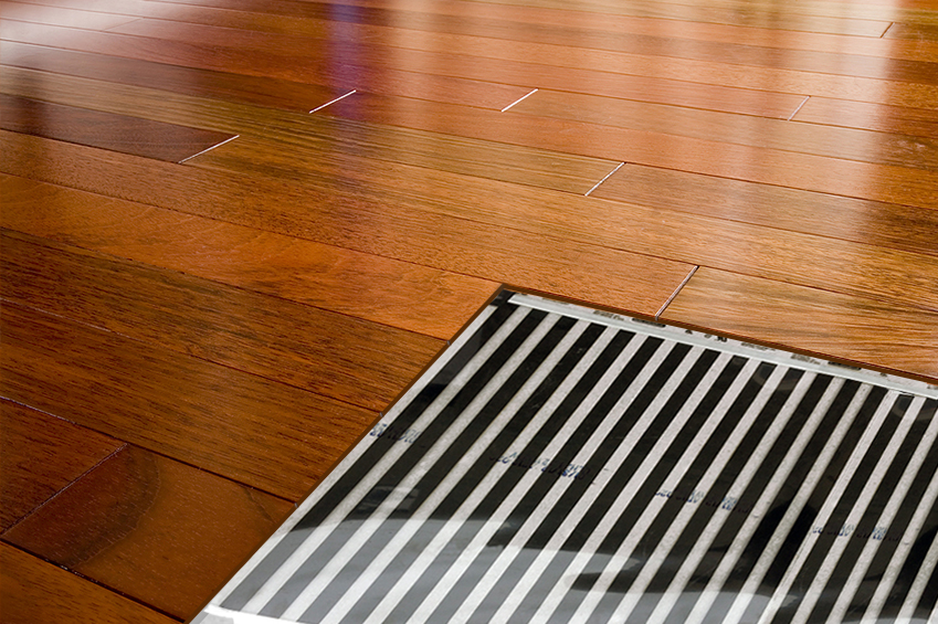 Large photo with cutout showing FilmHeat floor heating element installed under hardwood floor.