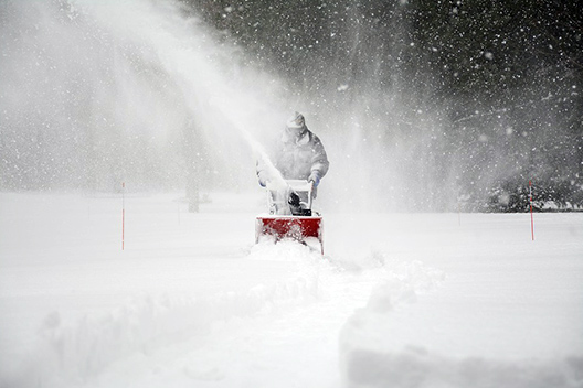 Clearing sidewalks with a snow blower.